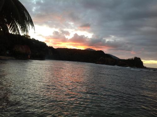 a body of water with a sunset in the background at Rainbow Beach Apartment in Calibishie