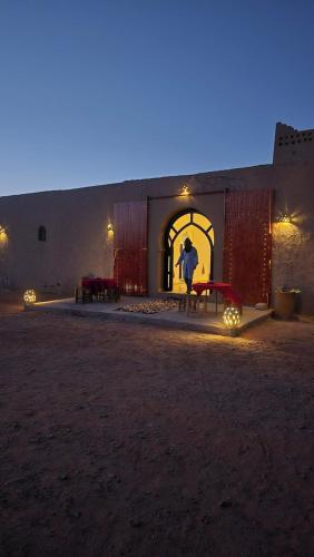 a man standing in front of a building at night at Riad Ouzina TGM in Ouzina