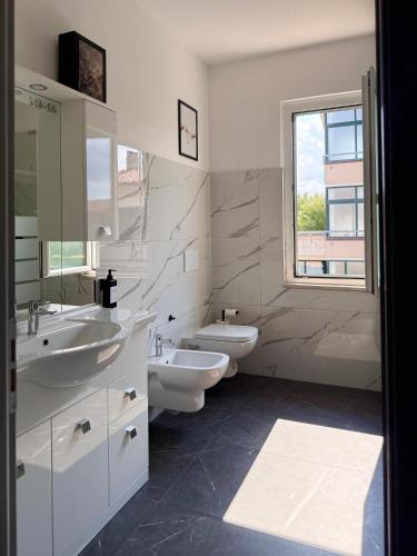 a bathroom with two sinks and a toilet and a window at Cecilia Sirmione Appartamento in Sirmione