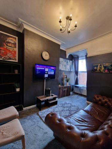 a living room with a leather couch and a tv at Kings Road Modern Home in Middlesbrough