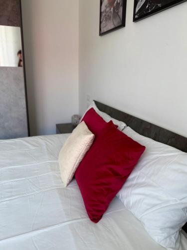 a red pillow sitting on top of a white bed at Cecilia Sirmione Appartamento in Sirmione