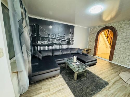a living room with a black leather couch and a table at Ferienhaus Adler in Unterlüß