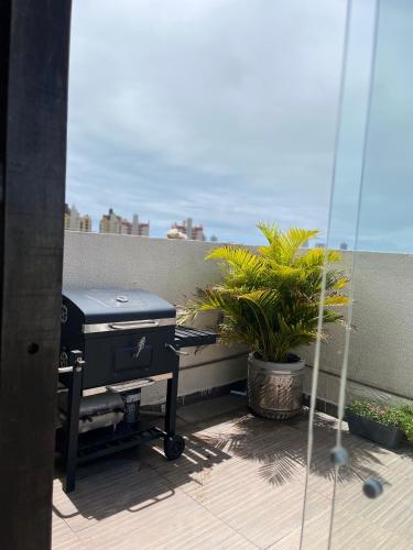 a patio with a grill and a plant on a balcony at Apartamento Amplo in Natal