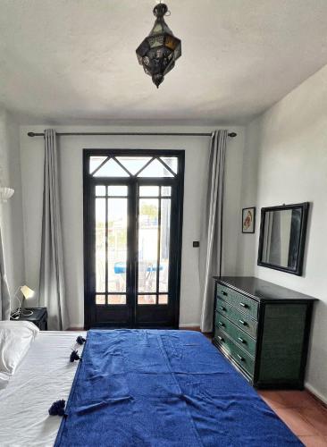 a bedroom with a large bed with a blue blanket at Duplex 3 pour les familles in Oualidia