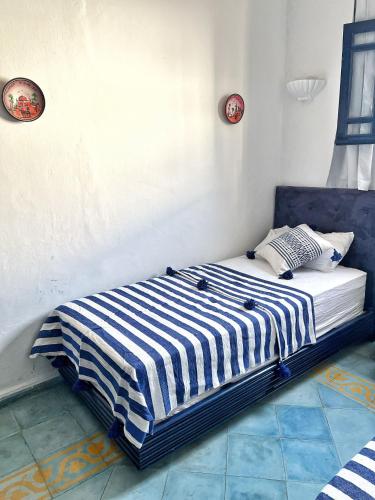a bed with a blue and white striped blanket on it at Duplex 3 pour les familles in Oualidia