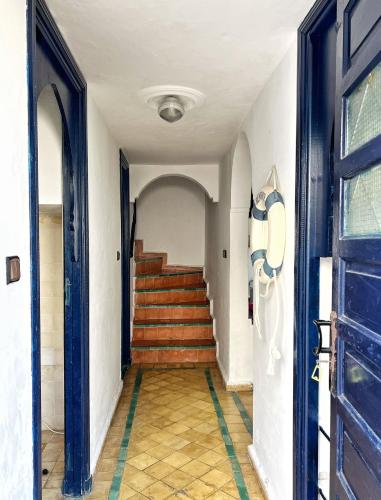 a hallway with stairs and a blue door at Duplex 3 pour les familles in Oualidia
