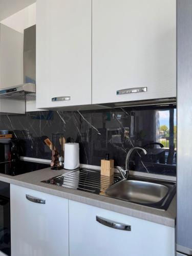 a kitchen with white cabinets and a sink at Cecilia Sirmione Appartamento in Sirmione