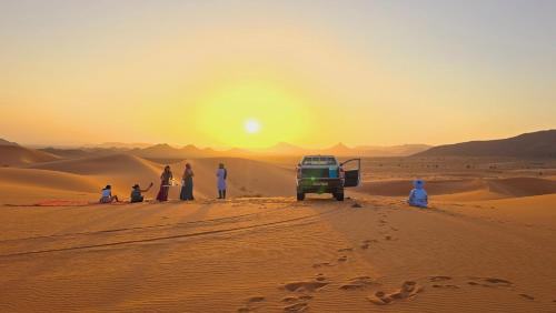 a group of people in the desert watching the sunset at Riad Ouzina TGM in Ouzina