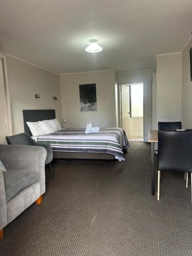 a bedroom with a bed and two chairs and a couch at Cherylea Motel in Blenheim
