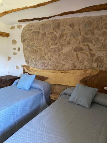 two beds in a room with a stone wall at El Masico Rural in Olba