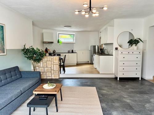 a living room with a blue couch and a kitchen at JUPAS - Premium Apartments in Konz