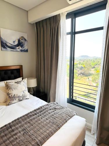 a bedroom with a bed and a large window at Menlyn Maine Residences in Pretoria