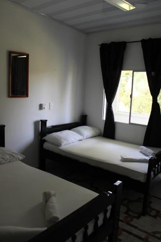 two beds in a room with a window at Posada Campestre brisas del camino in Puerto Triunfo