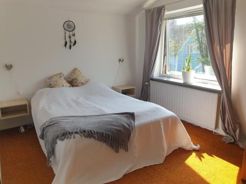 ein Schlafzimmer mit einem Bett und einem Fenster in der Unterkunft Cozy apt in 50s villa 10 min tram ride to city in Göteborg