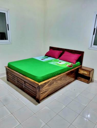 a bed with a green mattress and pink pillows on it at Guest house in Bissau
