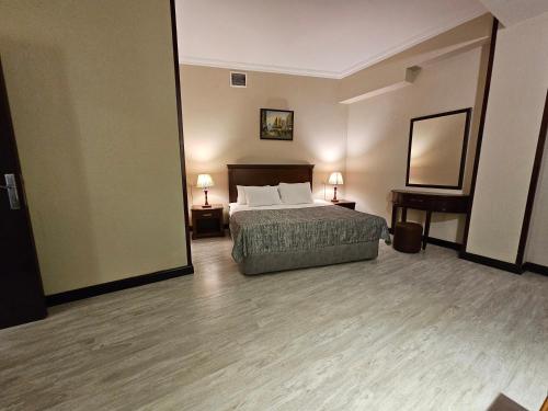 a hotel room with a bed and two tables and a mirror at Crown Suites in Baku
