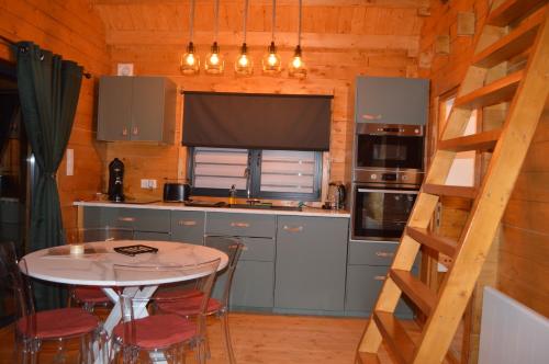 a kitchen with a table and a kitchen with a ladder at Le chalet de Joyce spa et piscine in Saint-Aubin-des-Préaux