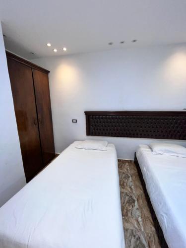 a bedroom with two beds and a cabinet at Hi pyramids view in Banī Ghālib