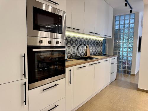 a kitchen with white cabinets and a stove top oven at Next to the Ski Lift Downtown Bansko in Bansko