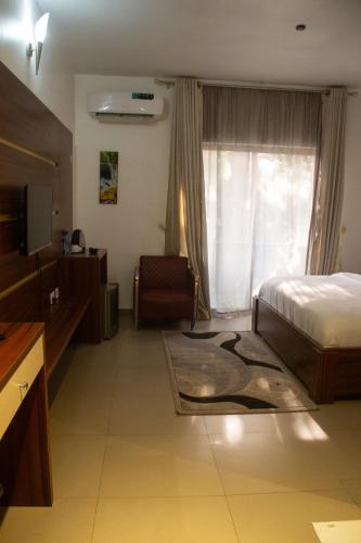 a hotel room with a bed and a tv and a window at Uranium Continental Hotel - UCH in Kaduna