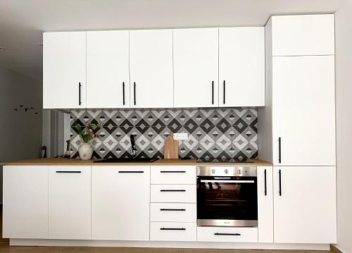 a white kitchen with white cabinets and an oven at Next to the Ski Lift Downtown Bansko in Bansko
