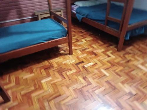 a room with two beds and a wooden floor at Hostel do Papai 3 in Lavras