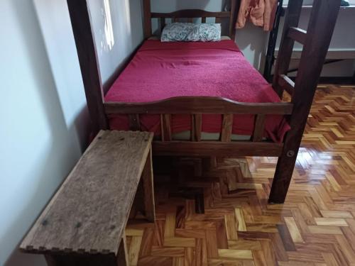 a small bed and a bench in a room at Hostel do Papai 3 in Lavras