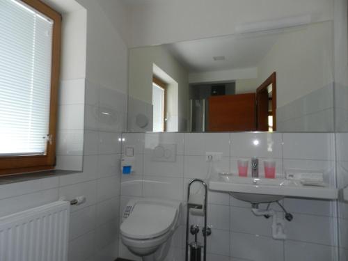 a white bathroom with a toilet and a sink at Hotel Rupertihaus in Heiligenblut