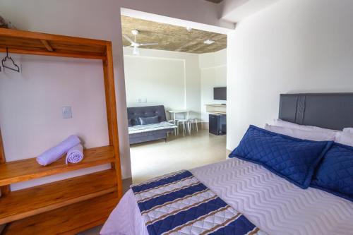 a bedroom with a bed and a living room at Pousada Assojuris in Caraguatatuba