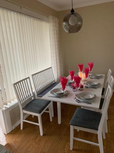 a white dining room table with red flowers on it at Apartment with a view in the center of Narvik in Narvik