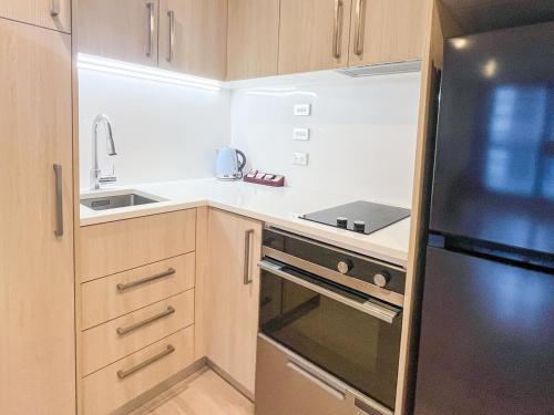 a small kitchen with a stove and a refrigerator at Stylish 2BR City Retreat with Cityscape Views, Pool & Gym in Auckland