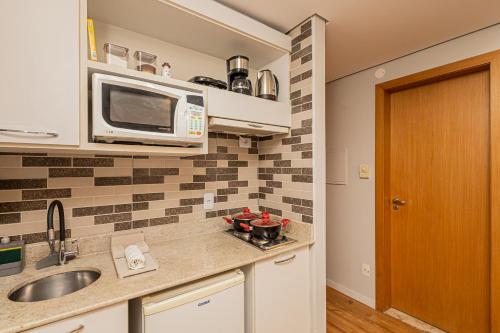 a kitchen with a sink and a microwave at STD - Anora Spaces - Stadium Alphaville in Barueri