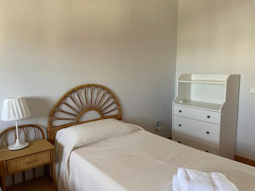 a bedroom with a bed and a dresser with a lamp at Casa Rural El Algarrobo in Utrera