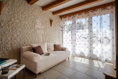 a living room with a couch and a large window at Calme et confort en Charente , Gîte Les Vignes avec piscine in Saint-Médard
