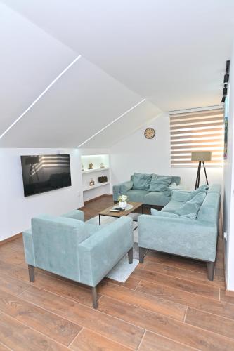 a living room with two blue couches and a tv at Lux&Spa Petko in Pirot