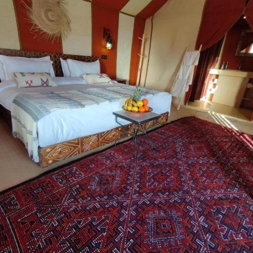a bedroom with a bed and a table with fruit on it at Sahara Soul luxury Camp in Merzouga