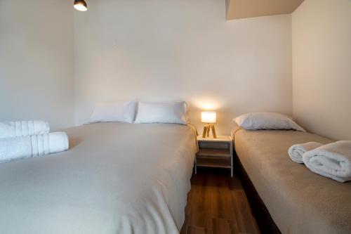 two beds in a small room with a lamp on a table at Luna Llena Dina Huapi in Dina Huapi