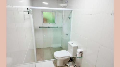 a white bathroom with a toilet and a shower at Maresias Suítes in Maresias