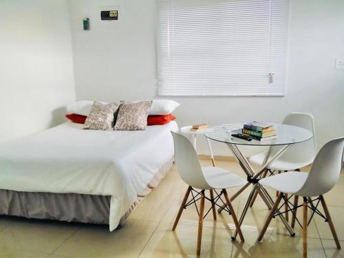 a bedroom with a bed and a table and chairs at The Royalty Ebukhosini 2 bedroom house in Teyateyaneng