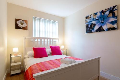 a bedroom with a bed with two pink pillows at 2 bedroom Large Town Centre Apartment FREE Parking in Loughborough