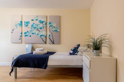 a bedroom with a bed and three paintings on the wall at 2 bedroom Large Town Centre Apartment FREE Parking in Loughborough