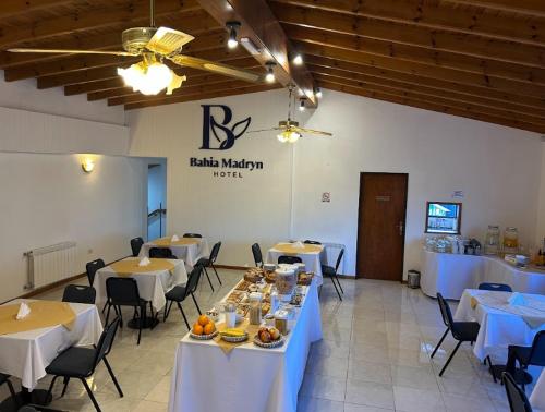 a dining room with tables and chairs with white tablecloths at Hotel Bahia Madryn in Puerto Madryn