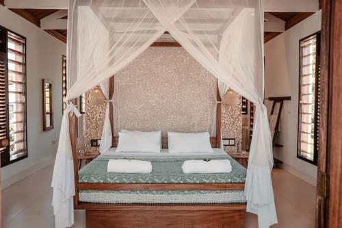 a bedroom with a canopy bed with two pillows at Fairy Forest in Diani Beach