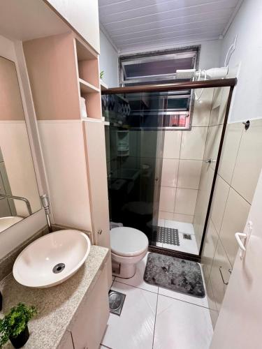 a bathroom with a sink and a toilet and a laptop at Estúdio aconchegante no centro com elevador in Nova Friburgo