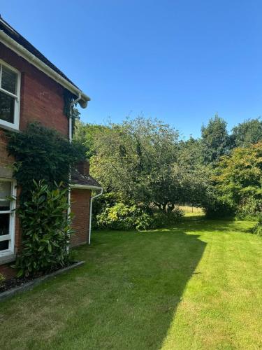 a yard next to a red brick house with a green lawn at Red House in Hinton