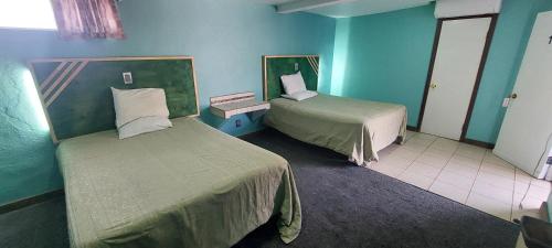 two beds in a room with blue walls at Motel la siesta in Tijuana