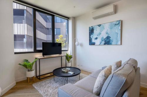 a living room with a couch and a tv at Chic Cosy 2BR Retreat with Rooftop Spa BBQ in Melbourne
