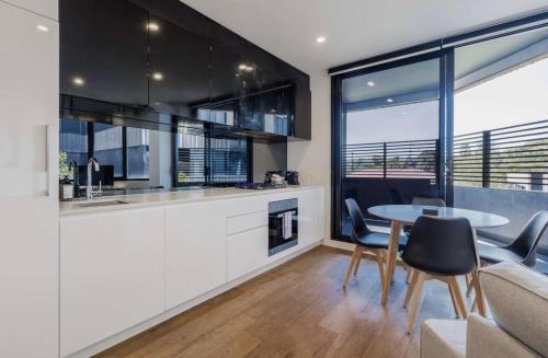 a kitchen and dining room with a table and chairs at Chic Cosy 2BR Retreat with Rooftop Spa BBQ in Melbourne