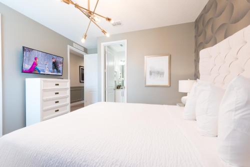a bedroom with a large white bed and a tv at Gorgeous Home With Private Pool, Themed Rooms Near Disney With Waterpark & Resort Access At Encore Resort - 7687Ff in Kissimmee