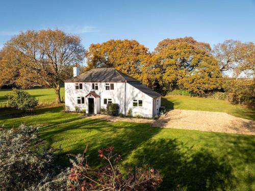 an old white house in a field with trees at Hobbs Cottage in Hinton